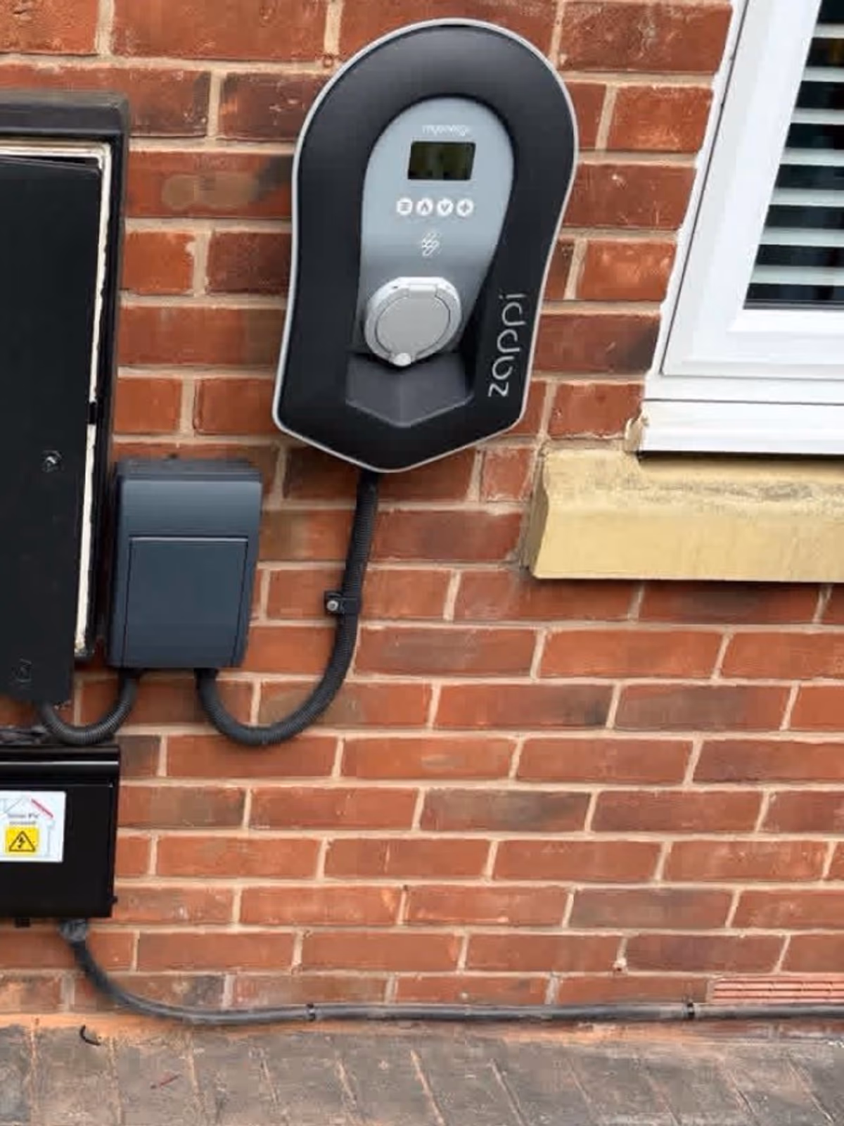 Zappi EV charger installed on a brick wall with neatly dressed cabling